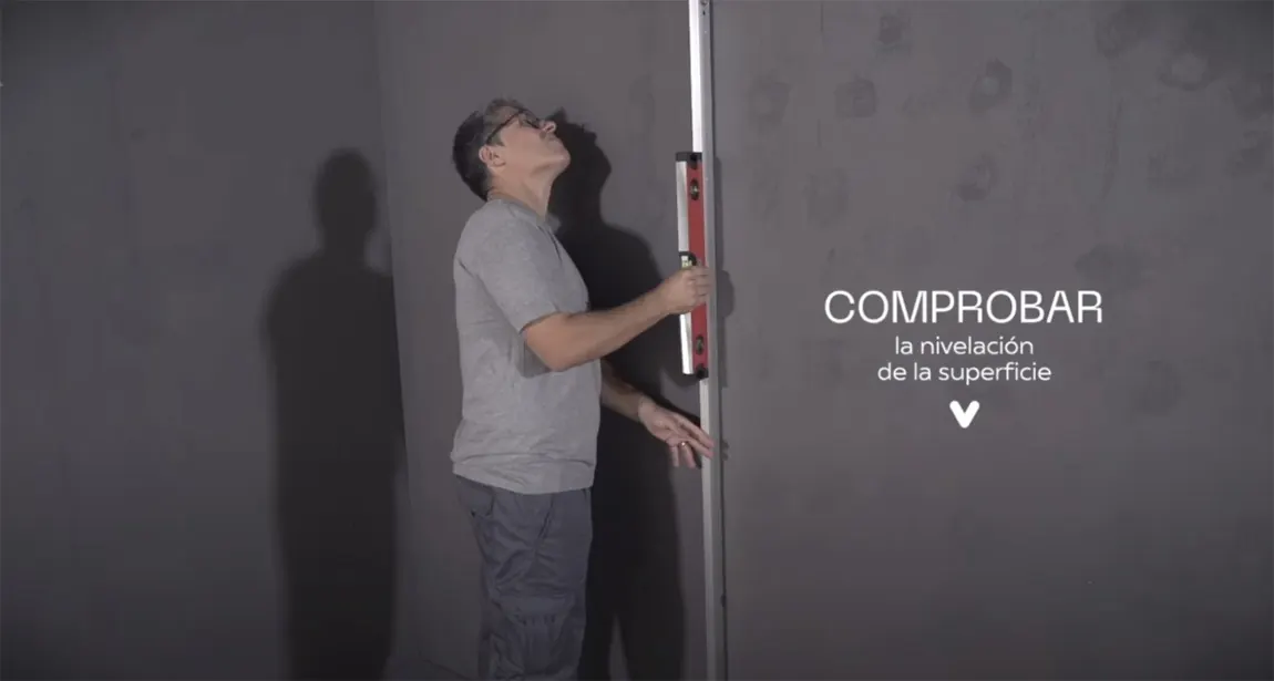 Colocador comprobando con un nivel la nivelación de la superficie